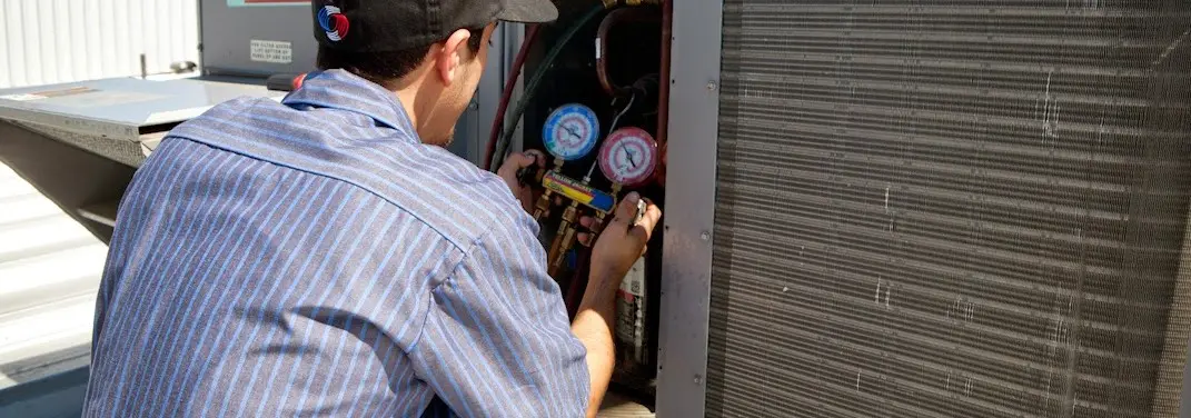 HVAC technician servicing a condenser unit in Pratt